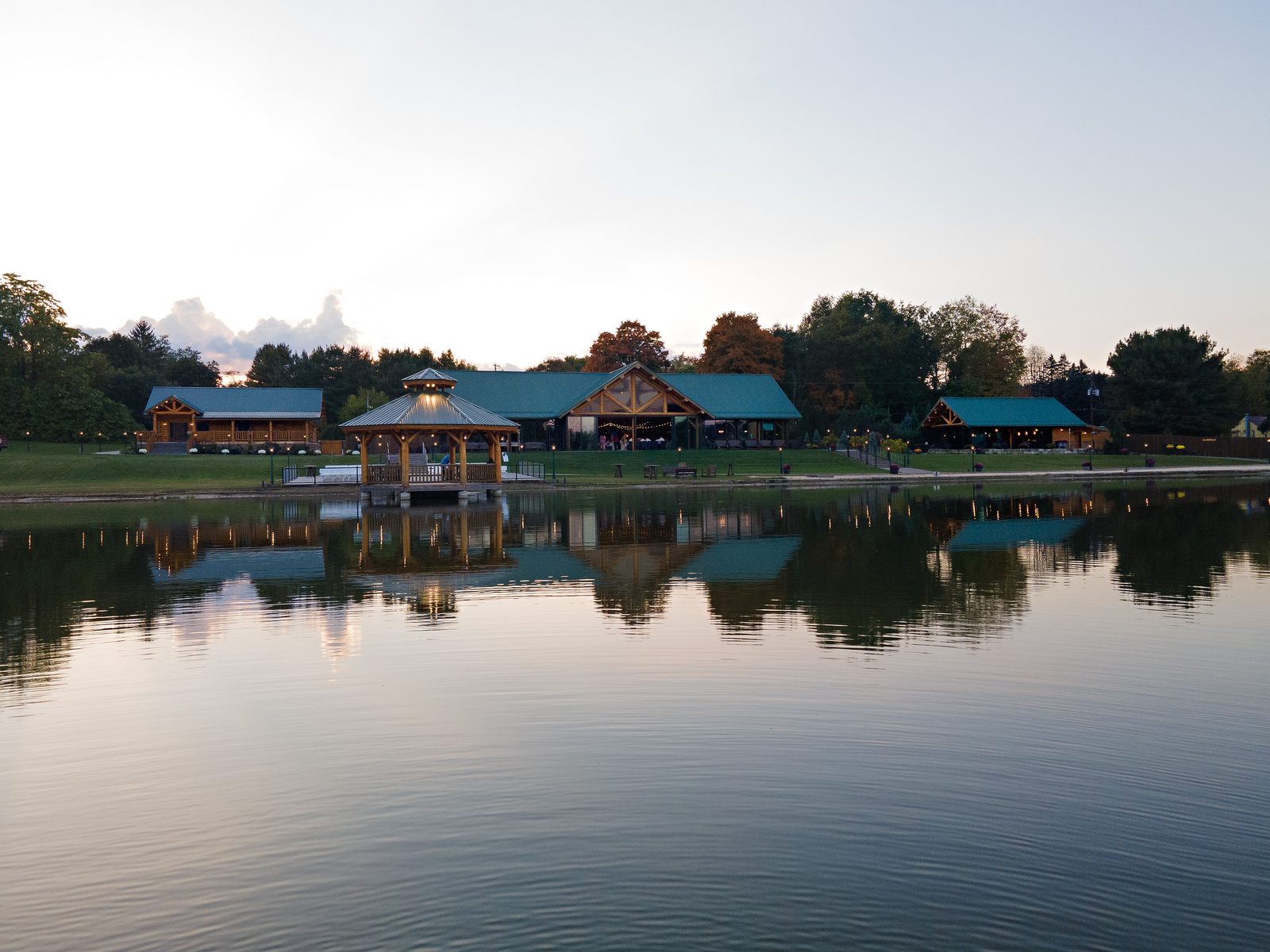 Drone shot of a lakeside lodge and pavilion reflected in the water at dusk