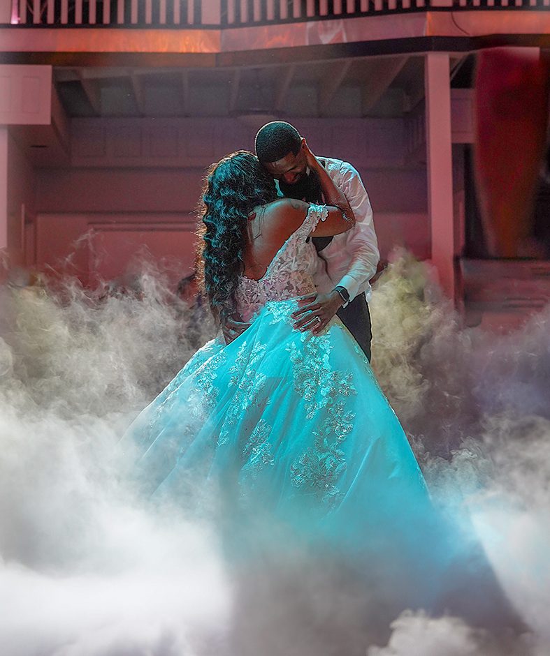 Cinematic video still of a couple dancing through low fog under red lights